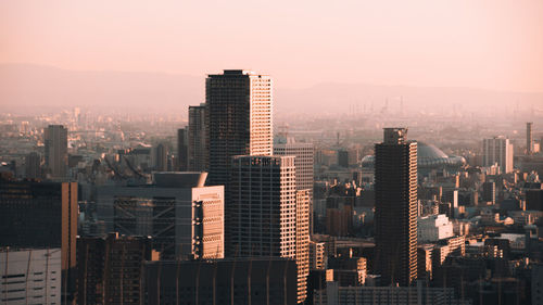 Modern buildings in city against sky during sunset