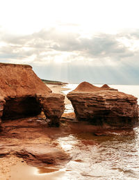 Rock formations at beach against sky