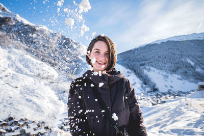 Portrait of smiling young woman on snowcapped mountains during winter