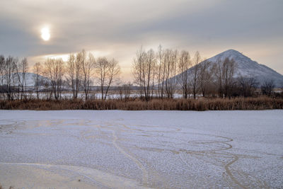 Snow covered landscape against sky during sunset