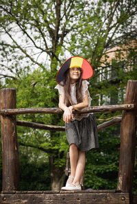 Portrait of young woman standing against tree