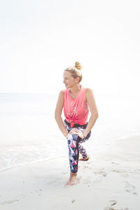 Full length of woman exercising on shore at beach