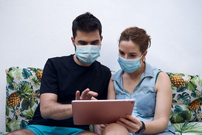 A couple with surgical masks choosing a holiday destination using a tablet. holiday concept