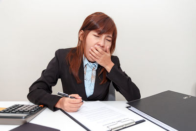 Young woman using mobile phone while sitting on table