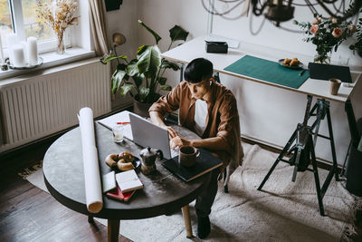 High angle view of male freelancer working on laptop while siting at home office