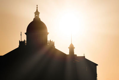 Dome of eastbourne pier as silhouette against early morning sunrise creating subtle lens flare.