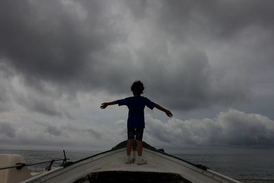 Rear view of man standing by sea against sky