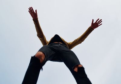 Low angle view of man with arms raised standing against clear sky