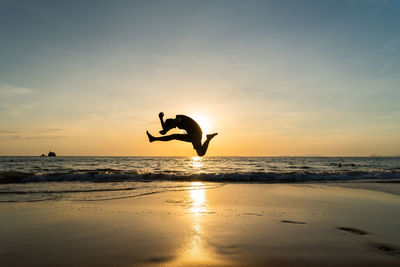 Silhouette man jump when sunset at phayam island, ranong, thailand.
