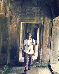 Full length portrait of young man standing against building