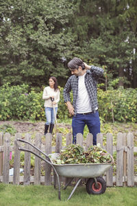 Confused farmer in front of weed wheelbarrow at organic farm