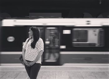 Woman standing against blurred train moving at station