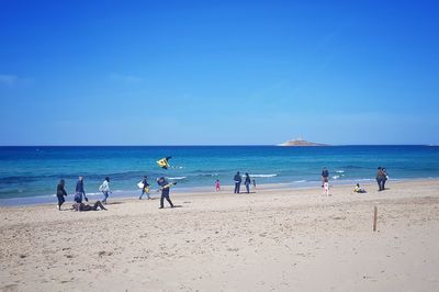 People on beach against blue sky