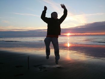 Silhouette of man standing on beach at sunset