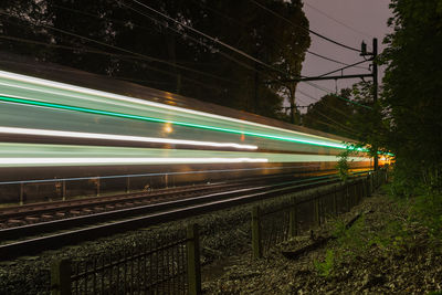 Light trails on railroad tracks against sky at night