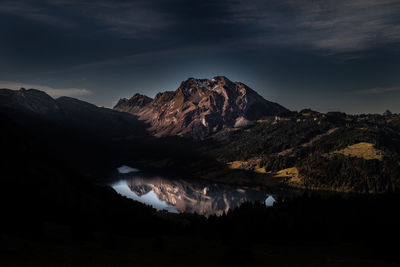 Scenic view of lake and mountains against sky at night