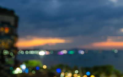 Defocused image of illuminated city against sky at sunset