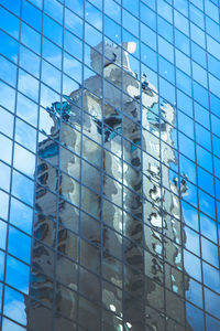 Low angle view of glass building against blue sky