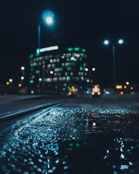 Close-up of wet street against sky at night