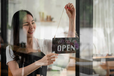Portrait of a smiling young woman holding glass window