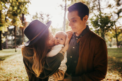 Loving young parents with cute infant child enjoying summer weekend together in green park