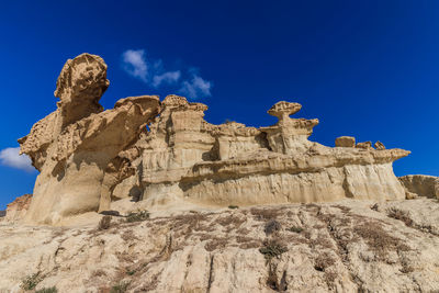 Low angle view of rock formation against clear blue sky