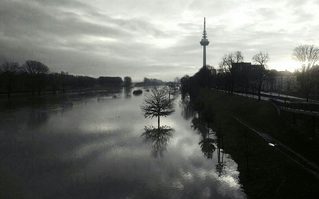 sky, water, cloud - sky, reflection, tree, cloudy, river, built structure, communications tower, cloud, lake, overcast, street light, nature, architecture, tranquility, waterfront, sunset, dusk, building exterior