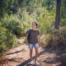 Full length portrait of teenage girl standing in forest