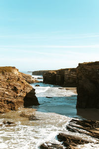 Rock formations on beach against sky