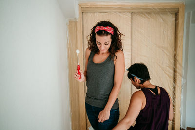 Beautiful woman standing against wall at home