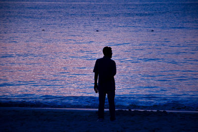 Rear view of silhouette man standing on beach