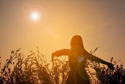 Low angle view of silhouette man holding sun during sunset