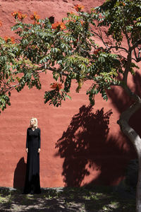 Tall woman in long dress standing in front of brown wall