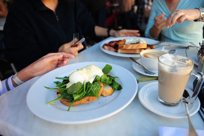 Midsection of friends with food and drink served on table