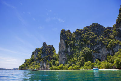 Rock formations by sea against blue sky