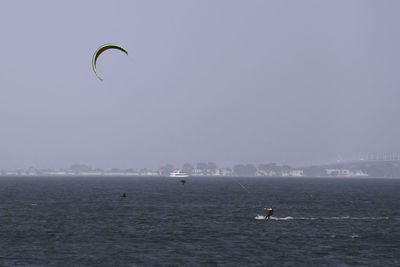 Man kiteboarding in sea against clear sky