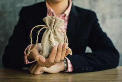 Midsection of businesswoman holding coins in sack on table