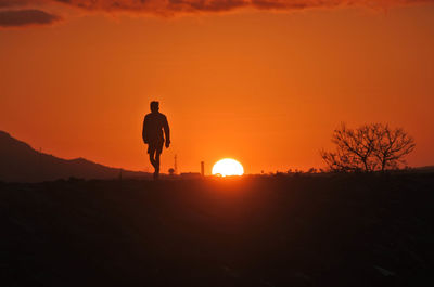 Silhouette woman standing on beach against sky during sunset