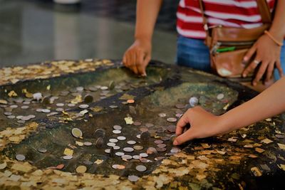 Midsection of people keeping coins at temple