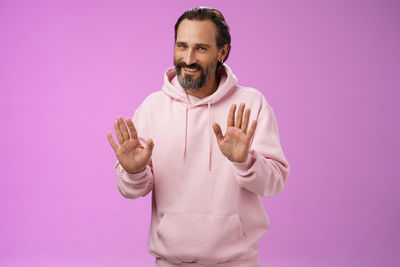 Portrait of man standing against pink background