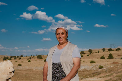 Portrait of a smiling young woman standing on landscape