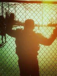 Rear view of a man seen through chainlink fence