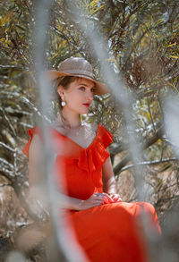 Young woman looking away while sitting on bare tree