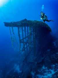 Person swimming in sea by shipwreck