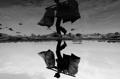 Low section of people hanging over lake against sky