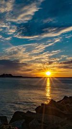 Scenic view of sea against dramatic sky during sunset