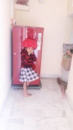 Full length of cute girl standing against wall