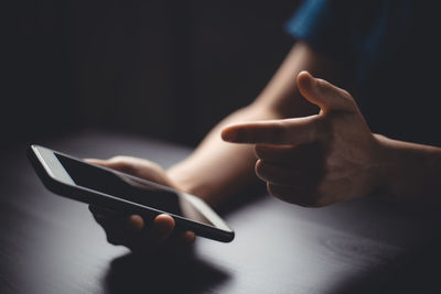 Close-up of hands using smart phone on table