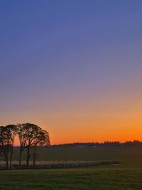 Scenic view of field against clear sky during sunset