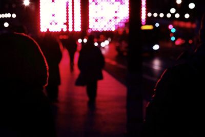 Silhouette people in illuminated city at night